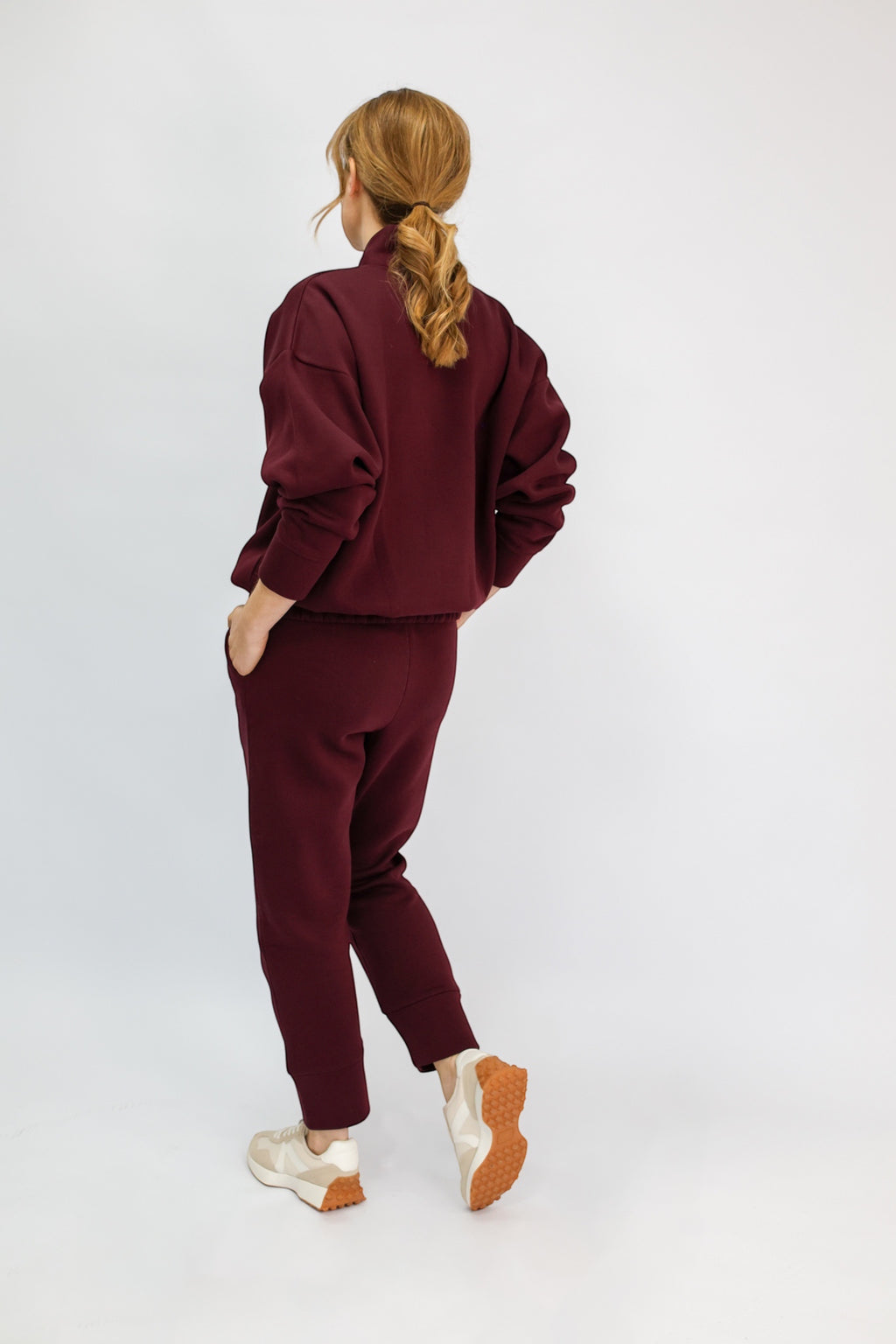 A model wearing a matching burgundy sweatshirt and jogger pants set.