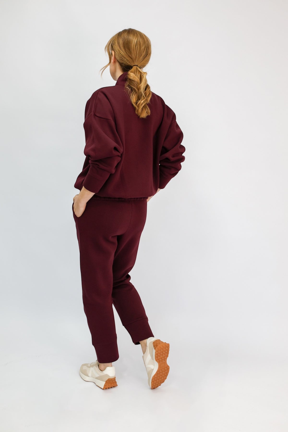A model wearing a matching burgundy sweatshirt and jogger pants set.