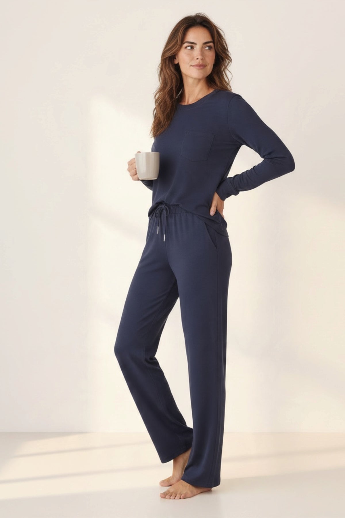 A woman modeling a navy blue long-sleeve lounge set with matching drawstring wide leg pants.