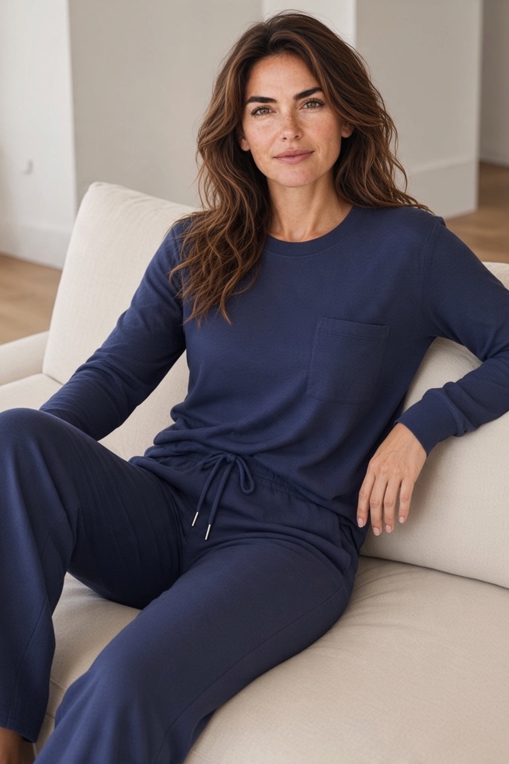 A woman wearing a navy blue long-sleeve crewneck top and matching navy blue wide leg pants.
