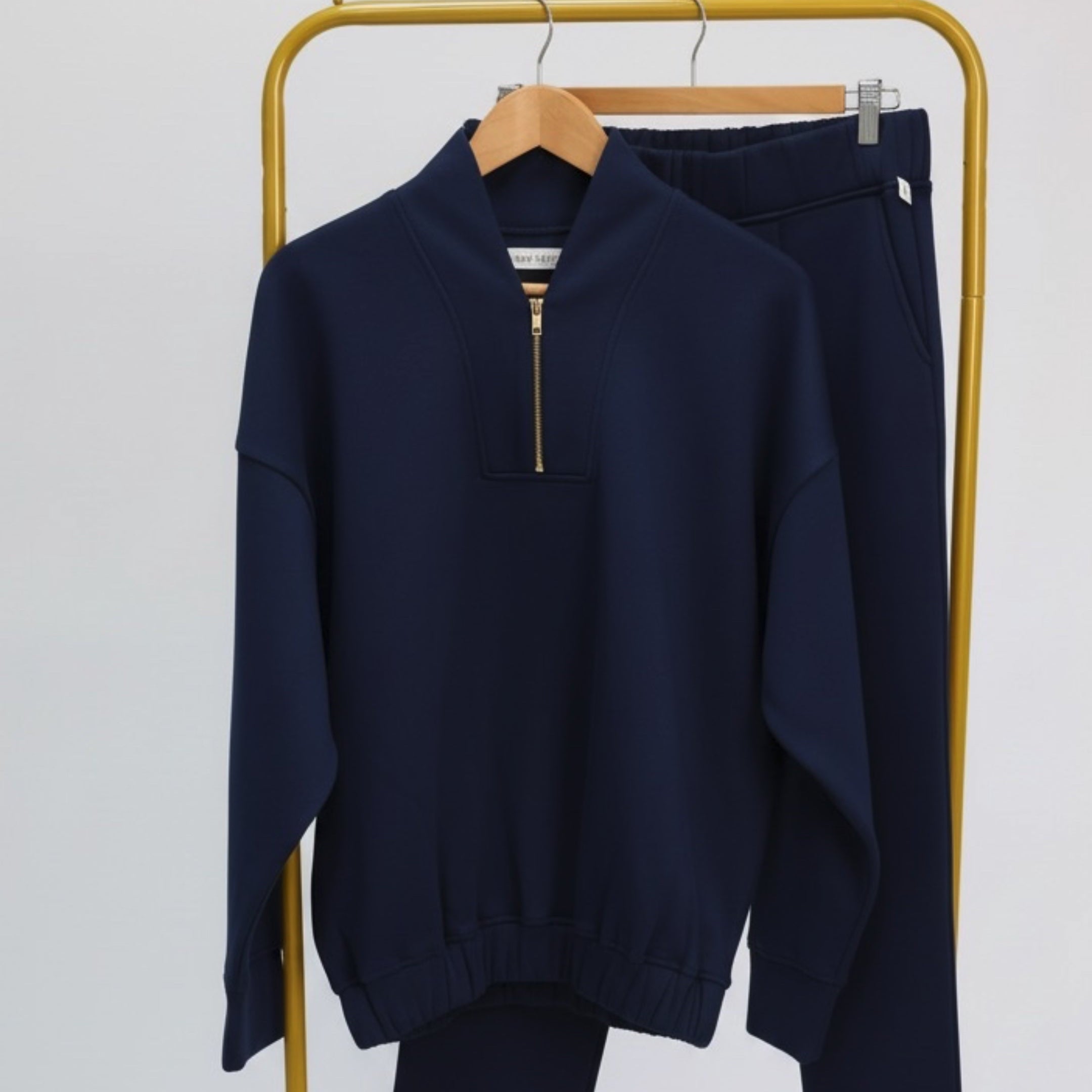 Navy blue coordinated set of sweatshirt and sweatpants on a brass rack