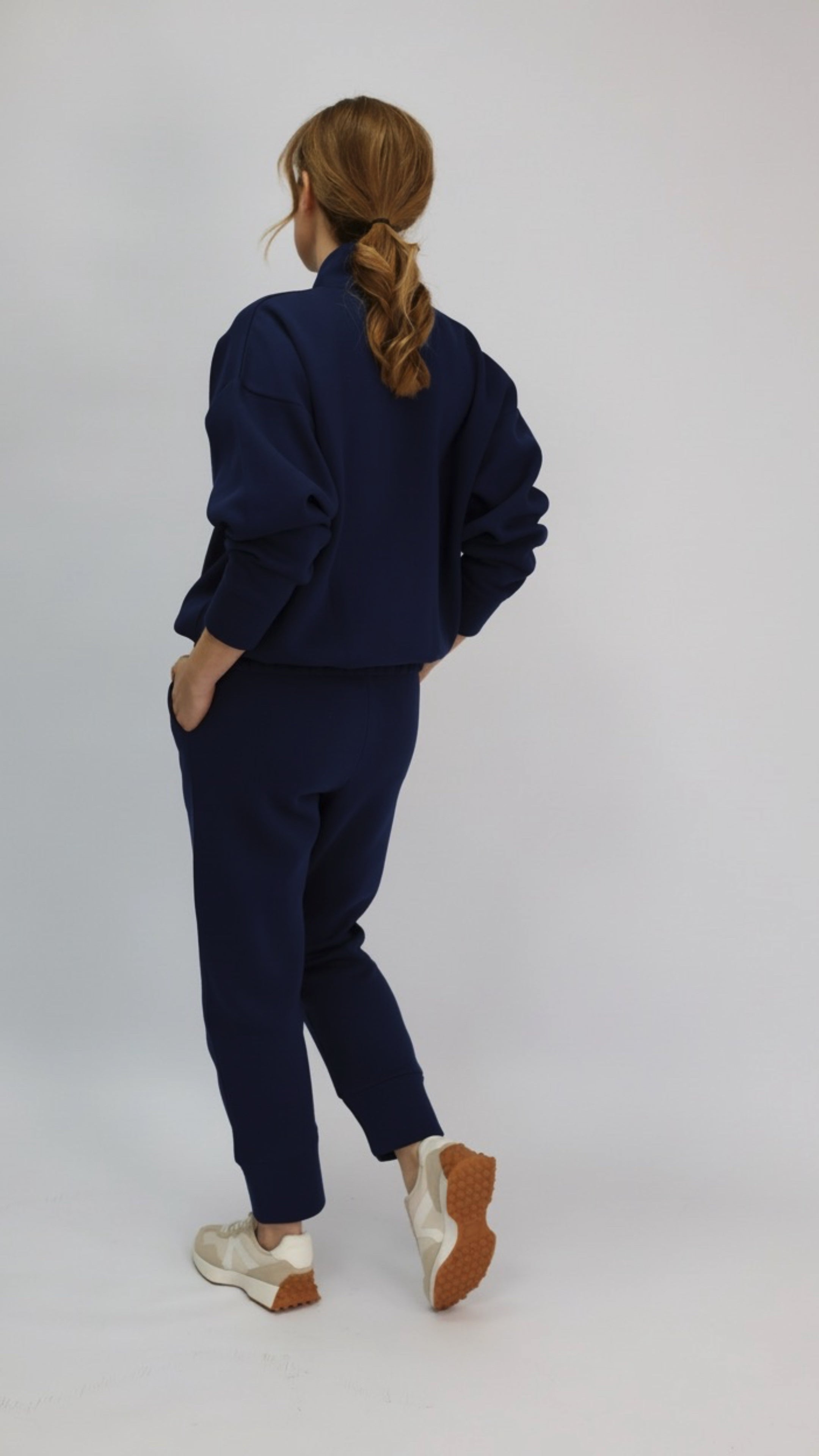 Model wearing a navy blue co-ord set of sweatshirt and joggers with white sneakers