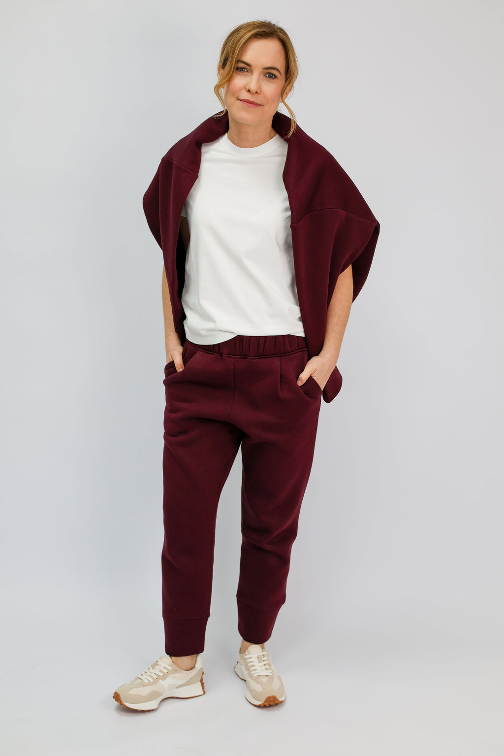 Tapered burgundy joggers and matching sweatshirt worn over the shoulders