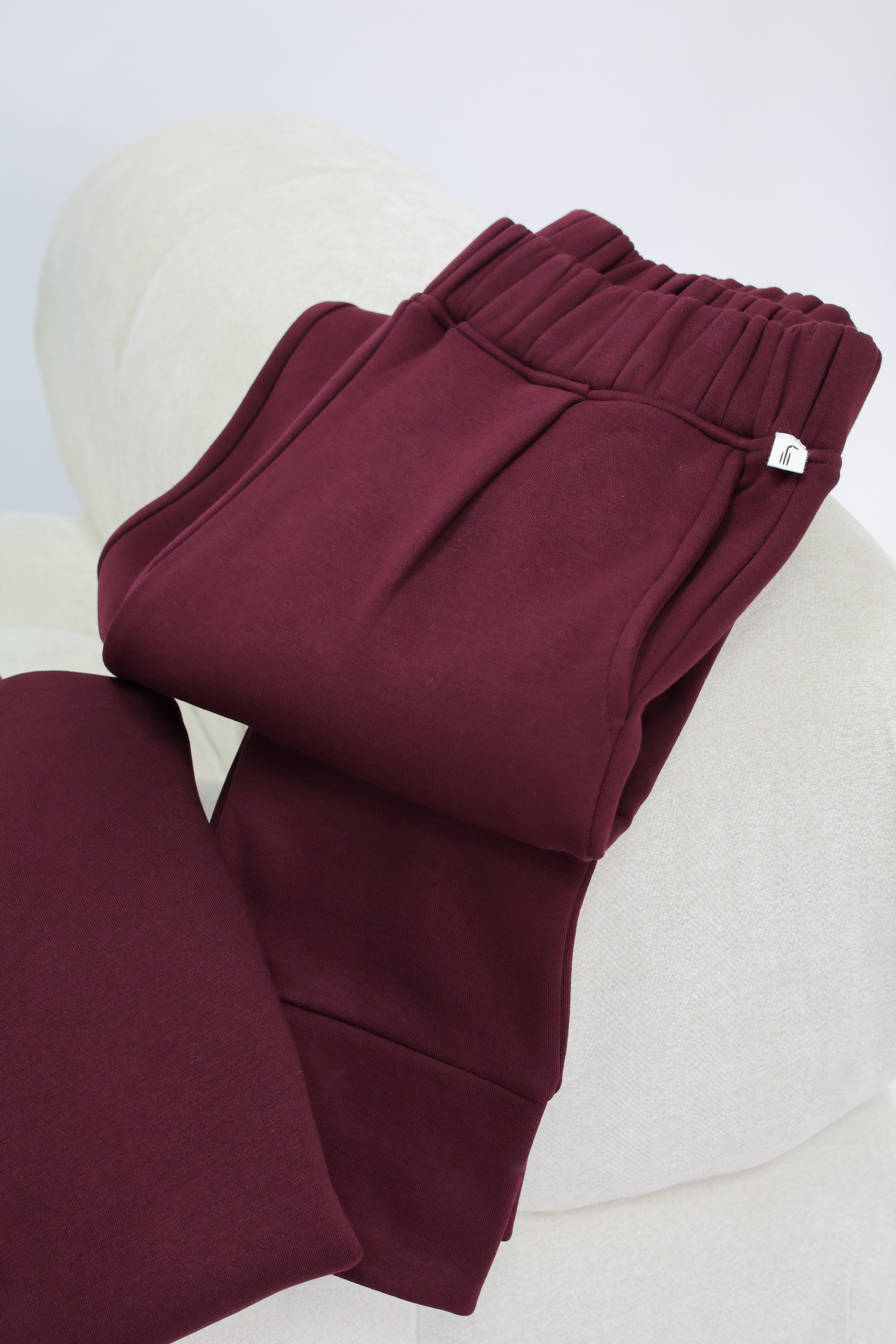 Detailed view of burgundy joggers with Wild Geese brand label