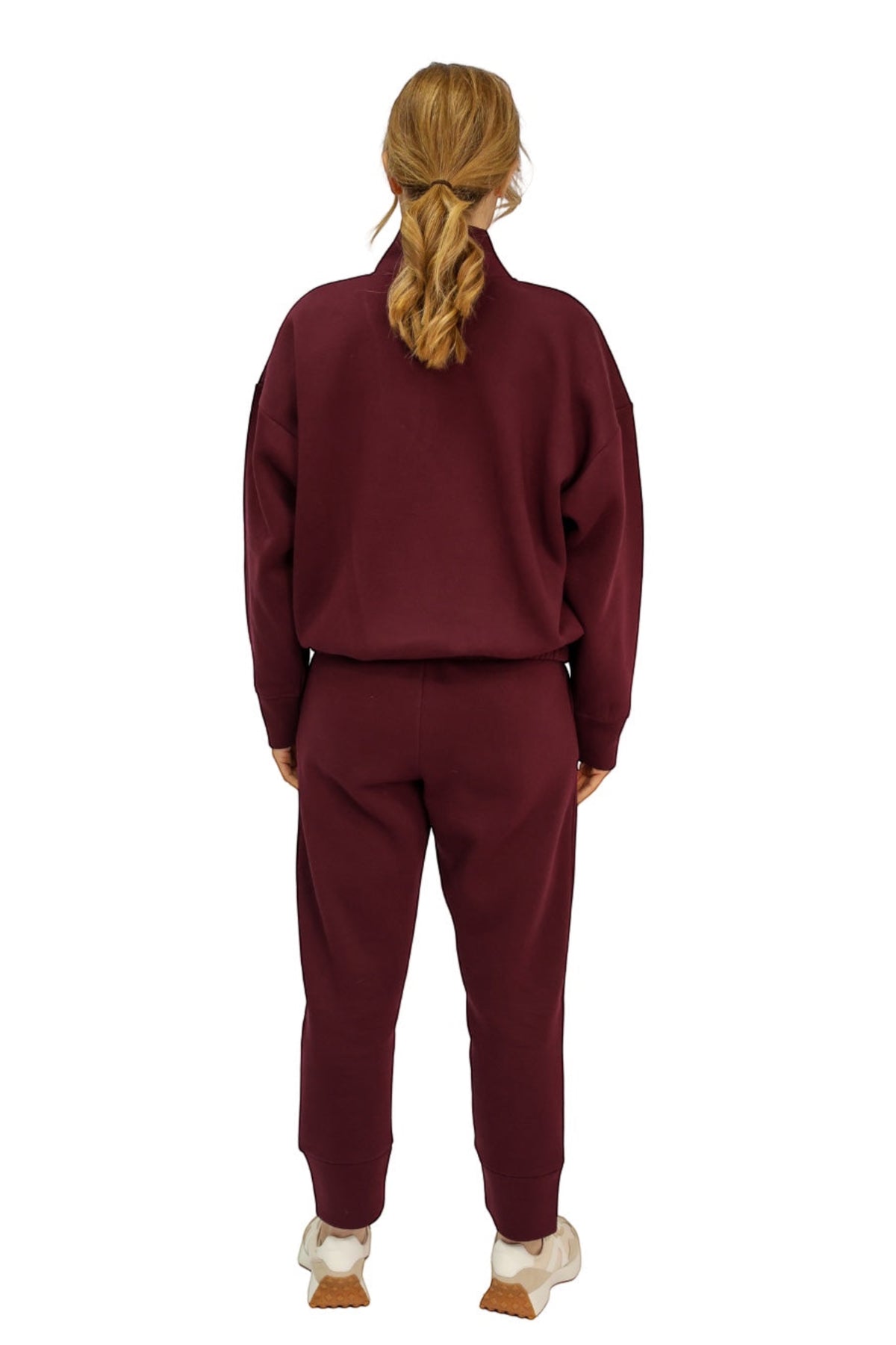 A woman viewed from behind wearing a matching burgundy tracksuit, consisting of a zip-up sweatshirt and jogger pants.