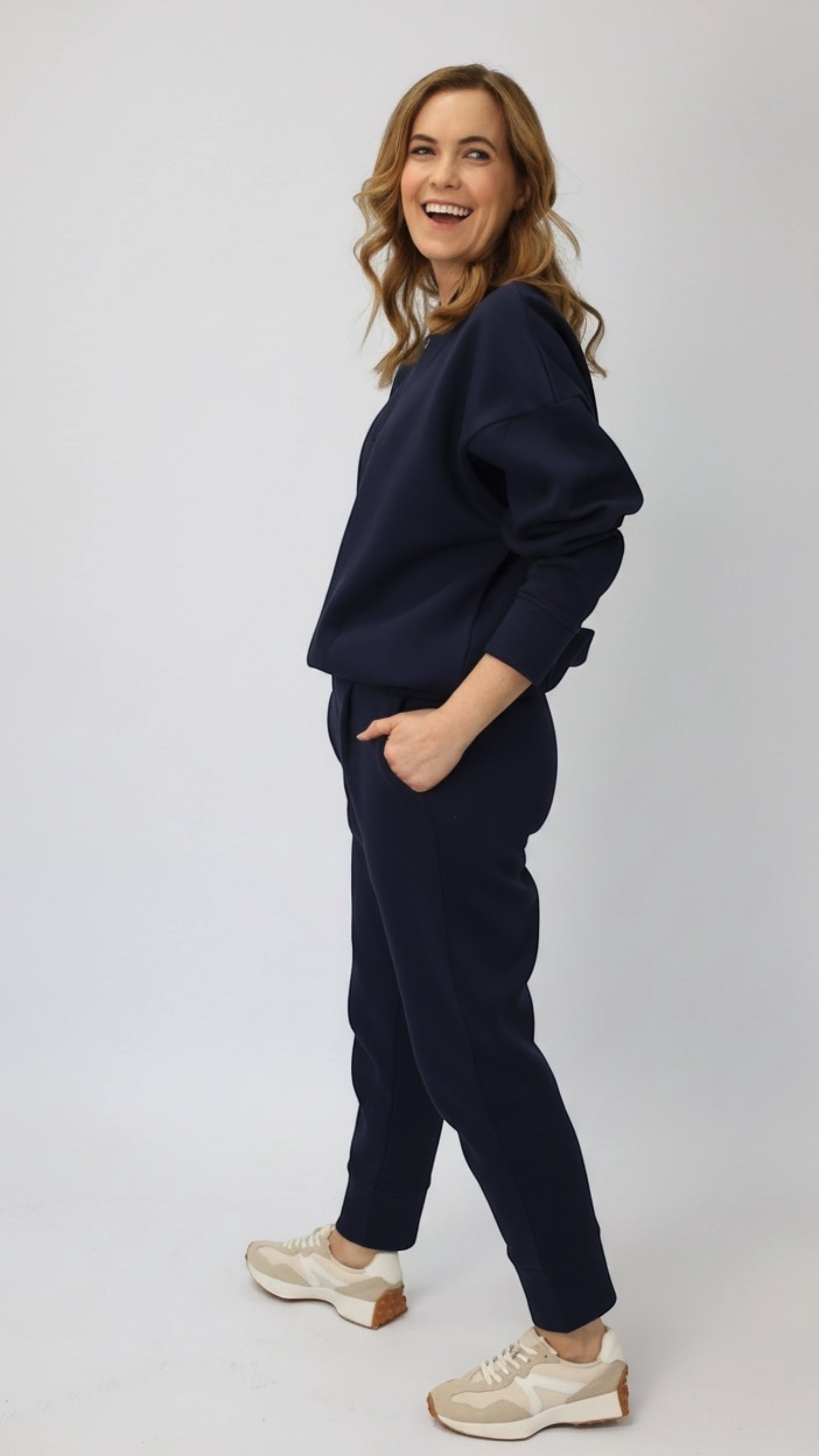 Wild Geese navy blue cotton fleece-lined cigarette sweatpants with front pleats and tapered legs, worn by a model.