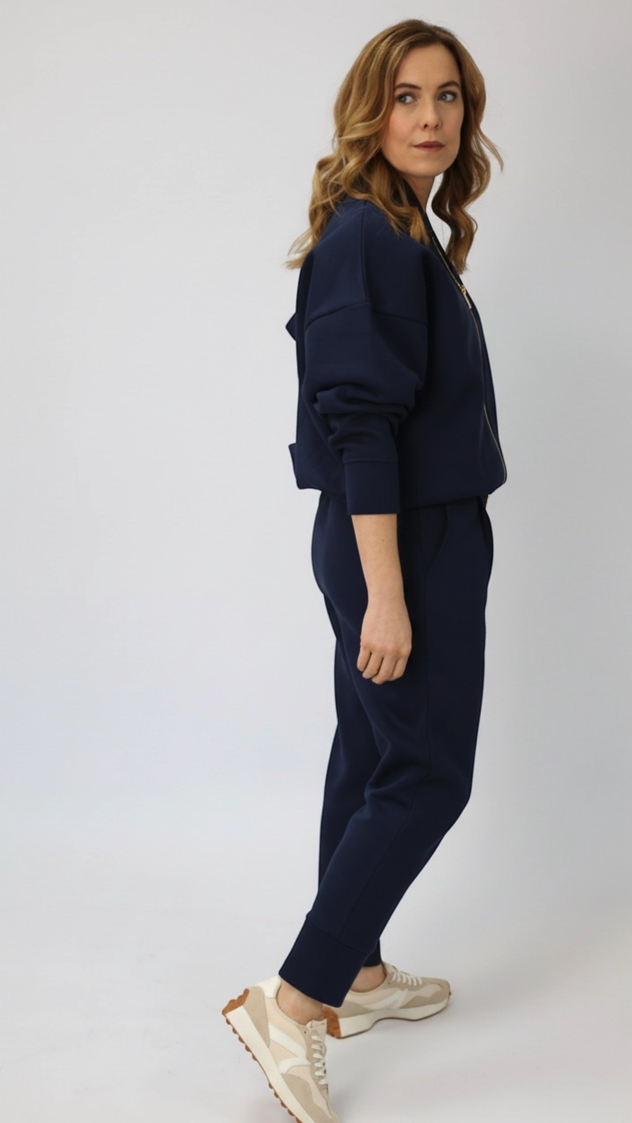 Wild Geese navy blue cotton fleece-lined cigarette sweatpants with front pleats and tapered legs, worn by a model.
